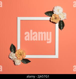 Creative layout made with spring flowers and white frame on pastel orange background. Season minimal idea. Nature background. Stock Photo