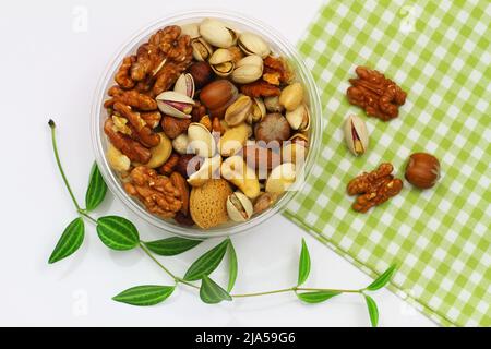 Pistachio nuts, walnuts, cashew nuts, hazelnuts, peanuts, almonds in plastic box on checkered cloth Stock Photo
