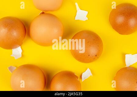 Many brown broken eggshells on yellow background top view Stock Photo