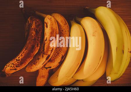 Bananas of different stages ripeness on a wooden background Stock Photo