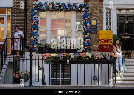 Chelsea, London, UK, 27th May 2022.Visitors pose with floral installations at Chelsea's annual free festival of flowers, 'Chelsea in Bloom', which runs from 23-28th of May 2022, This year the theme is 'British Icons'. Amanda Rose/Alamy Live News Stock Photo