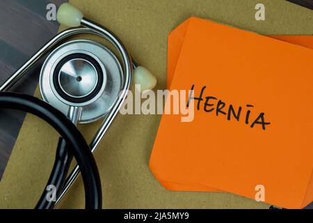 Concept of Hernia write on sticky notes isolated on Wooden Table. Stock Photo