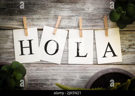 A set of printed cards spelling the word HOLA on an aged wooden background. Stock Photo