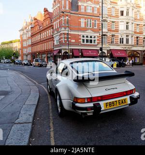 London, Greater London, England, May 14 2022: White Porsche 911 Carrera parked in Sloane Square Chelsea. French restaurant Colbert behind. Stock Photo