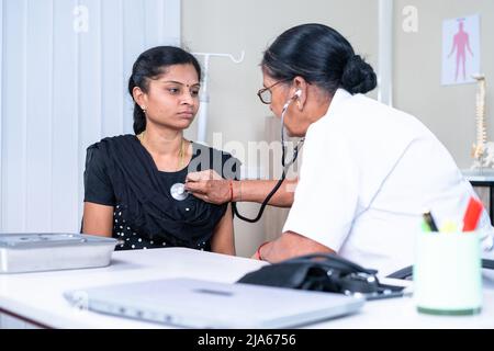 Doctor examining sick woman patient at hospital using stethoscope - conept of illness, medical treatment and healthcare problems Stock Photo