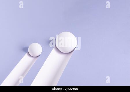 Large and small white rolling balls leave a trail on the purple background. Minimal abstract concept. Isometric rectangle layout. Stock Photo