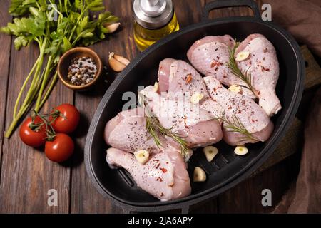 Raw chicken meat. Uncooked chicken legs on wooden cooking table background with spices. Stock Photo