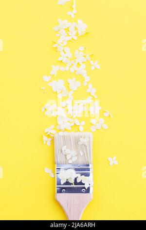 white hydrangea flowers and paint brush on a yellow background with copy space. Flat lay. Stock Photo
