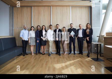 Diverse team of happy entrepreneurs or corporate employees standing in modern office Stock Photo