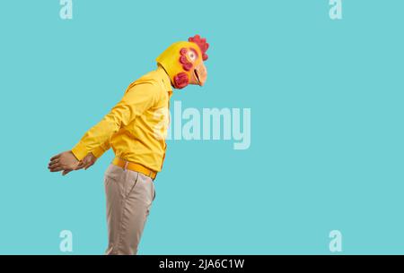 Side view of man wearing clothes and funny chicken mask getting ready to jump in water Stock Photo