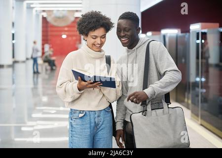 couple of students discussing a new book standing in the subway. Stock Photo