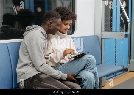 cute young couple with a digital tablet sitting in a subway car. Stock Photo