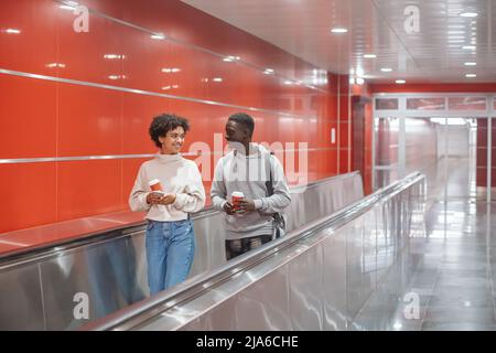 couple of students with a takeaway coffee going down to the subw Stock Photo