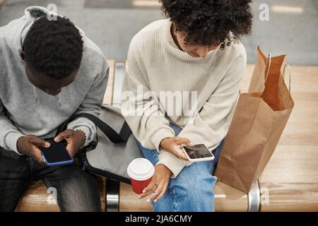 casual young couple using their smartphones waiting for the subway train . Stock Photo