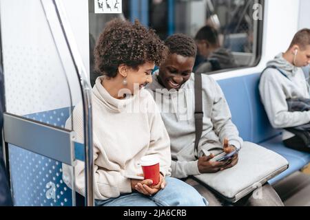 young couple using a smartphone while sitting in a subway car . Stock Photo