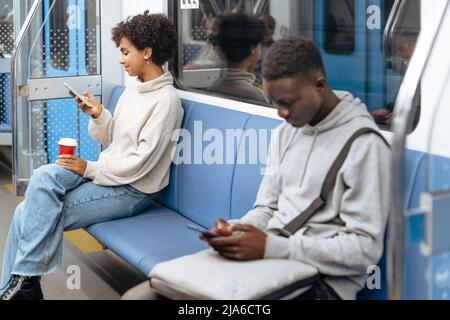 random subway passengers using their smartphones while sitting i Stock Photo
