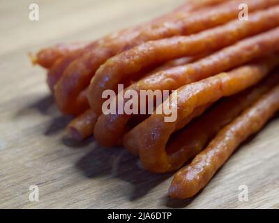 Traditional Polish sausages Kabanos on a wooden surface, macro photo. Kabanos, also known as cabanossi or kabana, is a long, thin, dry sausage usually Stock Photo