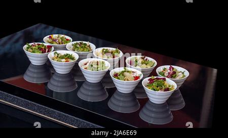 Green vegan salad from green leaves mix and vegetables, side view. set with different salads on table Stock Photo