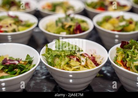 Green vegan salad from green leaves mix and vegetables, side view. set with different salads on table. close-up Stock Photo
