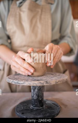 Creative handicraft process woman artist uses tool for shaping and hand sculpting pottery. working table in a workshop where a potter works with raw Stock Photo
