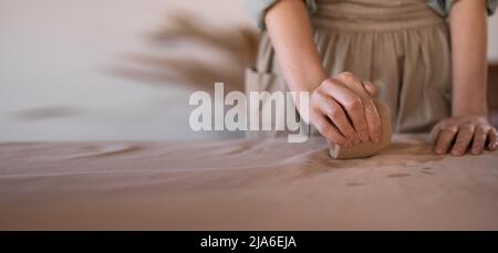 ceramist at work, using tools to create a handmade cup in the studio, selective focus. Close-up of female pottery hands forming handmade utensils in Stock Photo