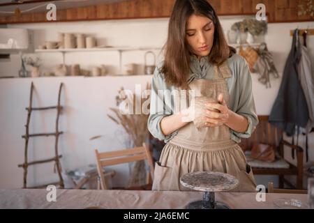 woman potter works with raw materials, creative process of needlework, creating handicraft ceramics. ceramist engaged in the molding and hand Stock Photo