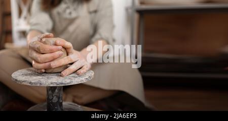 A woman works on a potter's wheel. An artisan molds a cup from a clay pot. Workshop of hand molding. close-up, Stock Photo