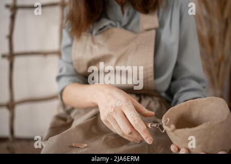 pottery and workshop with clay art concept. close-up on the hands of young woman ceramist with jug of unbaked clay. craftsman's working hands hold Stock Photo