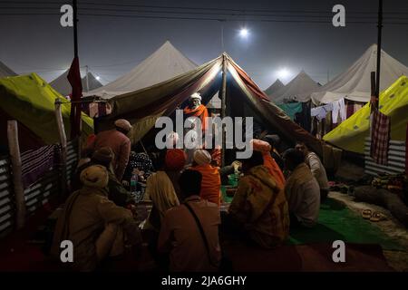 Sadhus meet outside of one of their tents during the Kumbh Mela festival. Every twelve years, millions of Hindu devotees begin a massive pilgrimage to the most sacred of Indian festivals: the Kumbha Mela, which takes place in Prayagraj, a place considered particularly auspicious because it is at the confluence of the Ganges, Yamuna and the mythical Saraswati. It is estimated that in 2019, 120 million people attended the sacred enclosure over the course of a month and a half. These numbers, equivalent to the total population of Japan, and 40 times the number of pilgrims who visit Mecca in the a Stock Photo