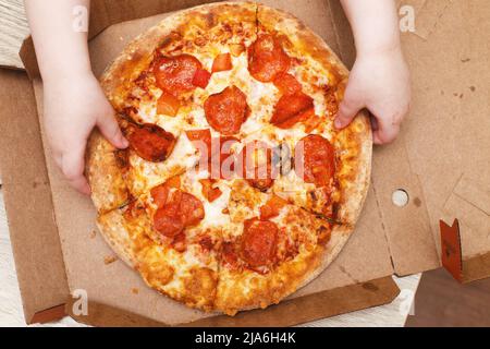 children's hands hold pizza in a cardboard box Stock Photo