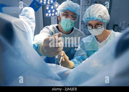Two surgery professionals making operation in pelvic area Stock Photo