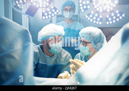 Nurse giving recommendation to surgeon during operation Stock Photo