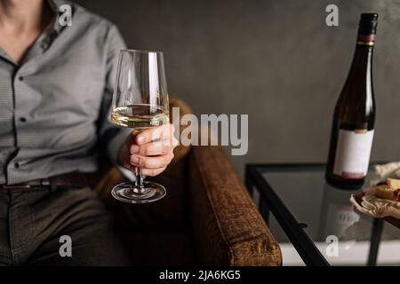 Man holding glass of wine while sitting on sofa Stock Photo
