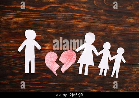 Paper chain cut family with broken heart on wooden background. Divorce and broken family concept. Stock Photo