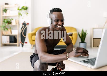 Happy young african man searching training video fitness program on laptop Stock Photo