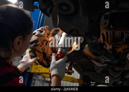 Female auto mechanic inspecting car parts in repair service station Stock Photo
