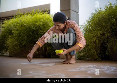 Indian Woman drawing rangoli Kolam on ground Stock Photo