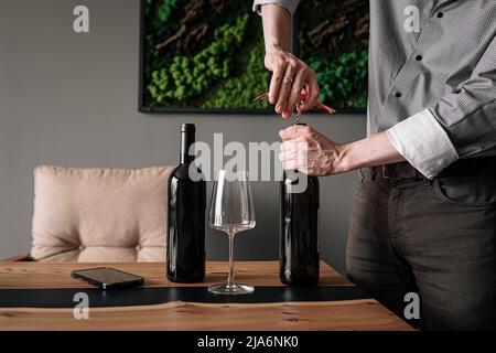 Man opening bottle of wine with corkscrew Stock Photo