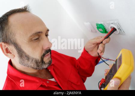 electrician testing plug socket with multimeter Stock Photo