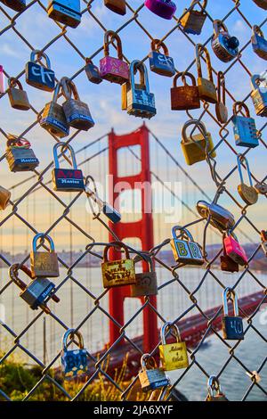 Chain link fence covered in locks with Golden Gate Bridge in distance Stock Photo