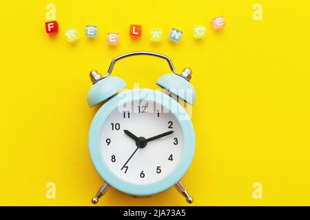 Alarm clock and word freelance made from multicolored plastic cubes of beads on a yellow background Stock Photo