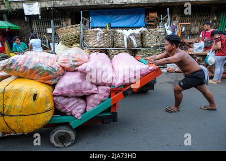 Cebu, Philippines - May 2022: A man carrying vegetables at the Carbon Market on May 25, 2022 in Cebu, Philippines. Stock Photo