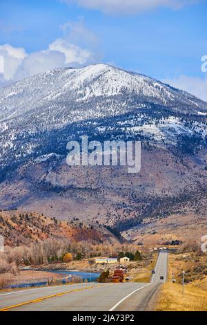 Endless road leading into huge snow-covered mountains Stock Photo