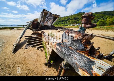Beach shipwreck falling apart after fire on beach Stock Photo