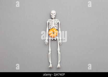 skeleton with pumpkin on grey background. halloween concept. Stock Photo