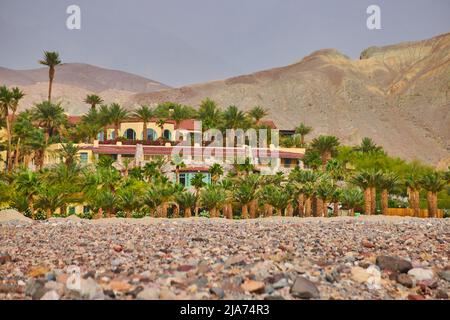 Desert plains and mountains surround a stunning hotel oasis filled with palm trees Stock Photo