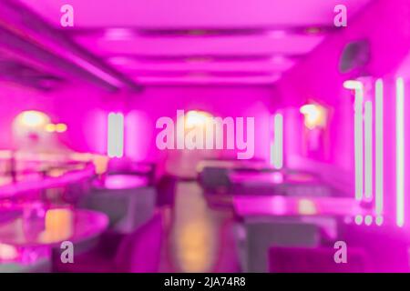 Blurred modern abstract interior of a nightclub with neon purple lighting on the walls. Stock Photo