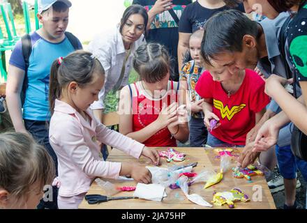 Zaporizhia/Ukraine- June 19, 2021:  Children participating in art and craft outdoors workshop, decorating cakes with colorful glaze. Children creative Stock Photo