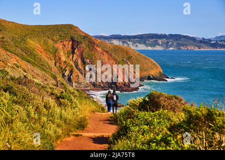 Couple walking towards beach from hill trail Stock Photo