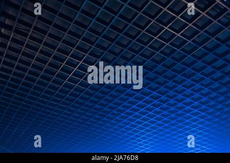 Geometric pattern ceiling grille in the dark with blue neon light abstract interior design, soft focus background. Stock Photo